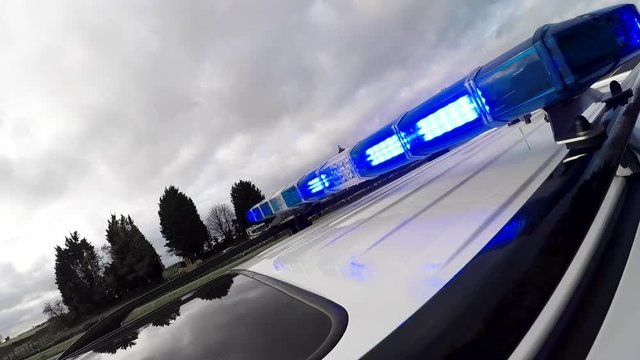 Stylised desaturated shot of police blue lights as patrol car speeds in response 