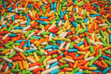 A wooden box filled to the brim with multicolored rainbow candies.