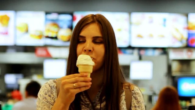 Young woman eating ice cream on the food court