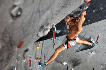 fitness, extreme hobbie, bouldering, people and healthy lifestyle concept - young positive male...