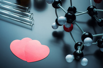 Two red paper hearts and molecular structure model on a black background. Love chemistry concept