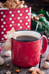 Red tea mug with cookies in Christmas decorations on a wooden table, selective focus