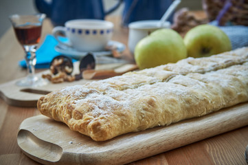 Apple strudel with nuts, raisins, cinnamon and powdered sugar. Homemade apple strudel with fresh apples. Country style apple strudel.