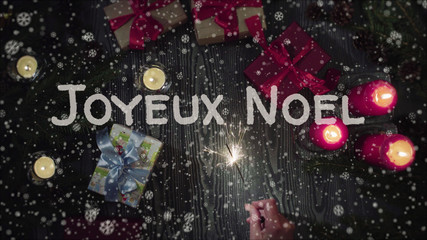 Greeting card Joyeux Noel, Merry Christmas in french language, falling snow, candles and gifts