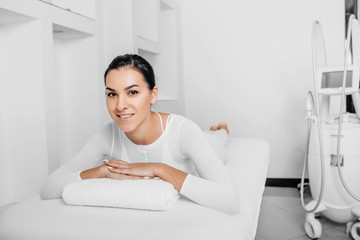 Beautiful happy woman lying on massage table after beauty therapy against cellulite with LPG...