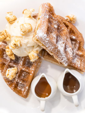 Waffle dressed with pop corn, ice cream and chocolate and caramel sauces