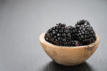 ripe blackberries in bowl on slate background