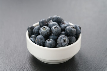 ripe blueberries in white bowl on slate background