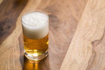 light beer in glass on wood background with copy space