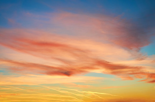 Multi-colored porous clouds at sunset with blue sky.