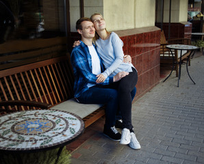 happy couple sitting outdoors in a cafe, the girl in the arms of the guy. smiling