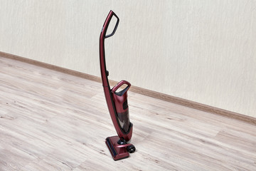 Upright red vacuum cleaner  in empty room.