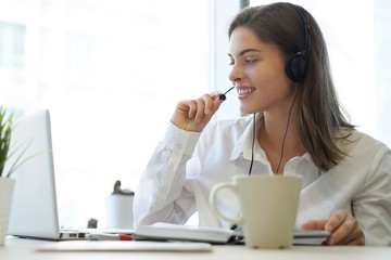 Woman customer support operator with headset and smiling.