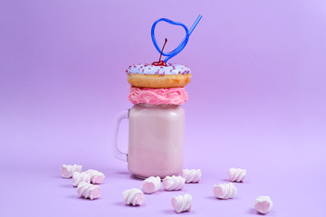 Pink strawberry freakshake with marshmallow and sweets.