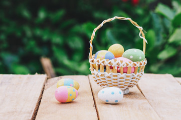Colorful easter eggs in basket on wooden table win copy space.