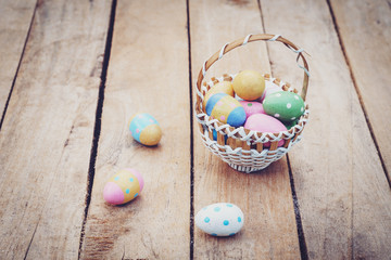 Colorful easter eggs in basket on wooden table win copy space.