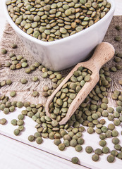 Green lentils in a bowl on a wooden background.