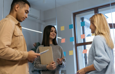 Group of happy multiracial business people working project, planning strategy, talking, discussion creative idea in modern office. Smiling colleagues meeting, collaborate, using sticky notes and scrum