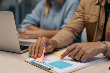 Close up of business man hands holding pink sticky note, working start up project, planning strategy, sharing idea, looking for solution in modern office. Presentation. Teamwork. Meeting