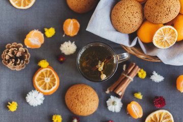 Tangerines, flowers, gingerbread, citrus in sraw basket, cup of tea and orange slices. Christmas winter background, wallpaper, greeting card. Top view, flat lay, background, copy spaces.