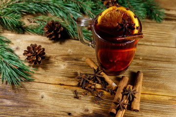 Christmas mulled wine with spices and fir tree branches and cones on wooden table