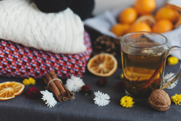 Tangerines, flowers, citrus in sraw basket, warm sweater, cup of tea and orange slices. Christmas winter background, wallpaper or greeting card. Top view, flat lay, background, copy spaces. 