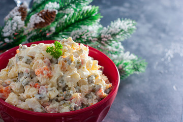 Traditional Russian New Year's salad in a red bowl with New Year's decor, horizontal, copy space