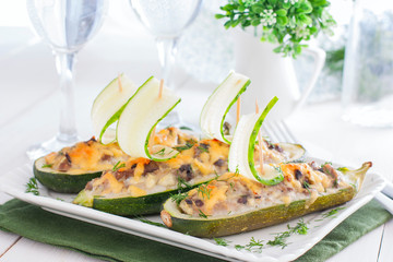 Festive stuffed with meat and mushrooms zucchini in the shape of boats decorated with fresh cucumber, horizontal