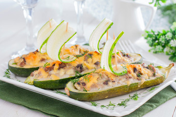 Festive stuffed with meat and mushrooms zucchini in the shape of boats decorated with fresh cucumber, horizontal