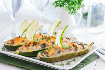 Festive stuffed with meat and mushrooms zucchini in the shape of boats decorated with fresh cucumber, horizontal