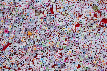 Many white cubes with colored letters and holes lie on a red background.