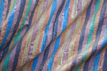 collored  stripes on the rough fabric with folds. rough surface texture. blue brown black yellow green and pink stripes on the rough fabric with folds. rough surface texture. colored fabric