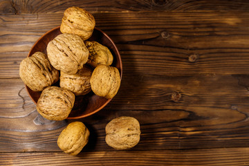 Walnuts in ceramic plate on wooden table. Top view