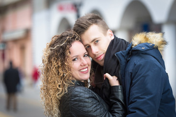 young couple embrace on street in winter