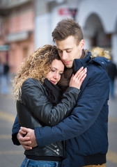 Fototapeta na wymiar young couple embrace on street in winter