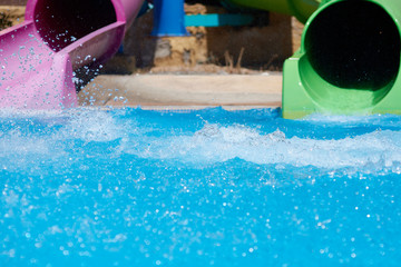 Two colorful pipes at the waterpark, pool and splases of the water around.
