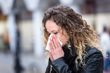 woman blowing nose with handkerchief in winter