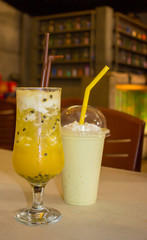 Cold delicious exotic cocktail of fresh fruit passion fruit in a misted glass with water droplets on the glass and avocado smoothies with whipped cream on the bar table