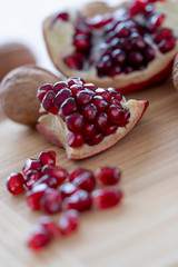 The pomegranates fruit, two nuts on the wooden plate