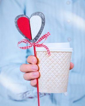 Woman in a blue shirt holding a crafted heart and a coffee cup, love, kindness, compassion St Valentines celebration concept