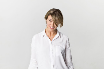 Happy young blonde woman wearing white shirt smiling portrait against white background