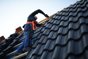 Dachdecker Bauarbeiter arbeitet am Arbeitsplatz mit Dachpfanne in schwarz und Werkzeug; Referenz...