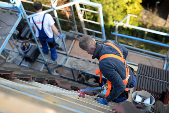 Dachdecker Firma auf Zimmermann Baustelle mit schwarzen Dachpfannen, Referenz im Hausbau mit Arbeitssicherheitseinweisung f&uuml;r den Dachdecker Facharbeiter auf dem Ziegeldach, Gesetz und Vorschriften