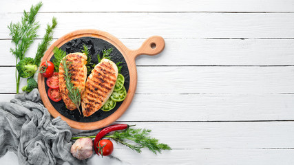 Baked chicken fillet with herbs and spices on a white wooden background. Top view. Free copy space.