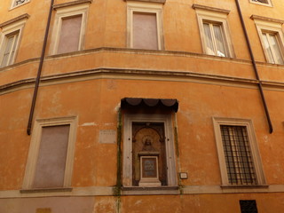 Fototapeta na wymiar Facciata di un antico palazzo con una nicchia religiosa a Roma in Italia. 
