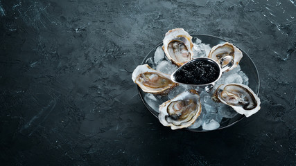 Oysters and black caviar in a plate of ice and lemon. Seafood. Top view. Free copy space.