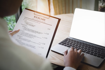 woman holding resume application with using computer laptop digital to job search on internet....