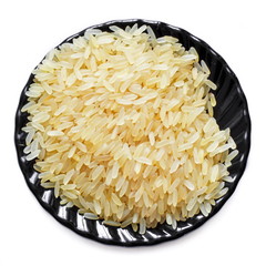 Black saucer with a handful of raw dry brown rice on a white background. Isolated