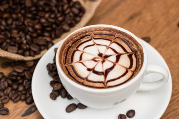 Hot coffee and coffee beans on wooden table.