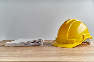 Stack document report with yellow engineer hat on wooden table